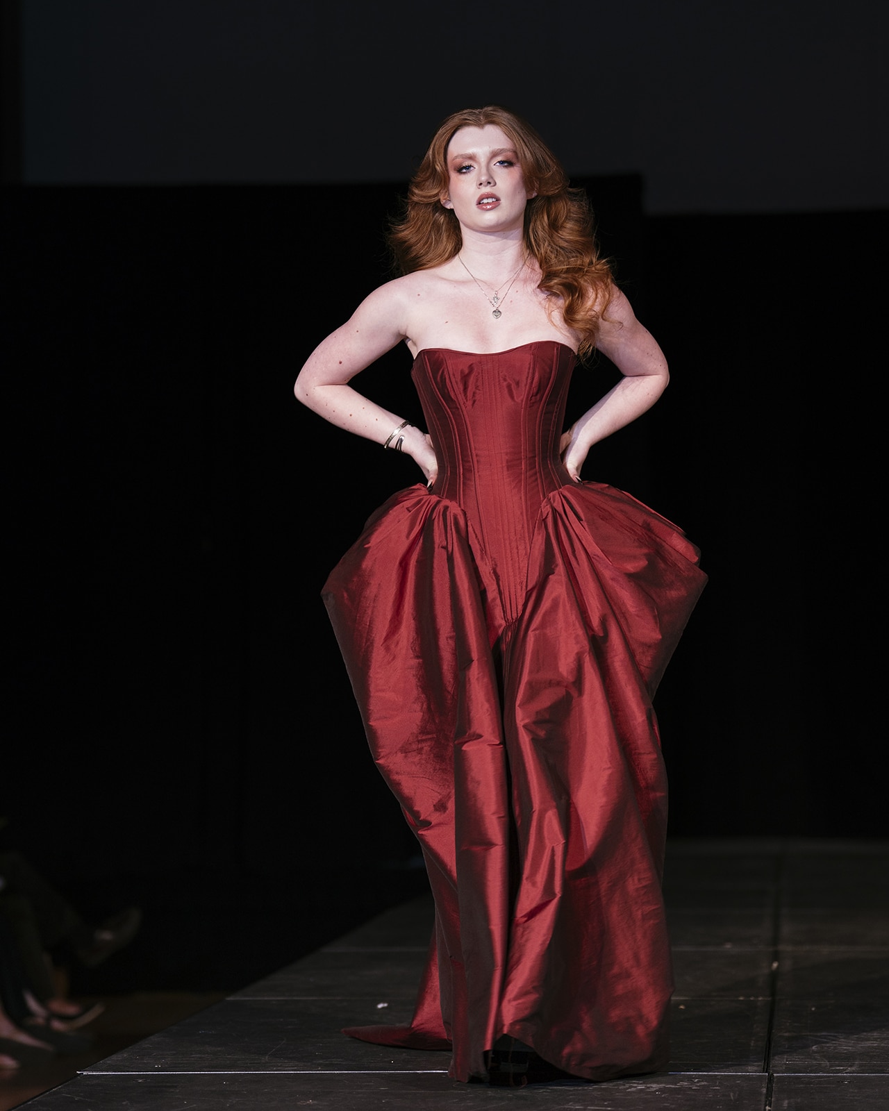 Model on the runway in a strapless red dress.