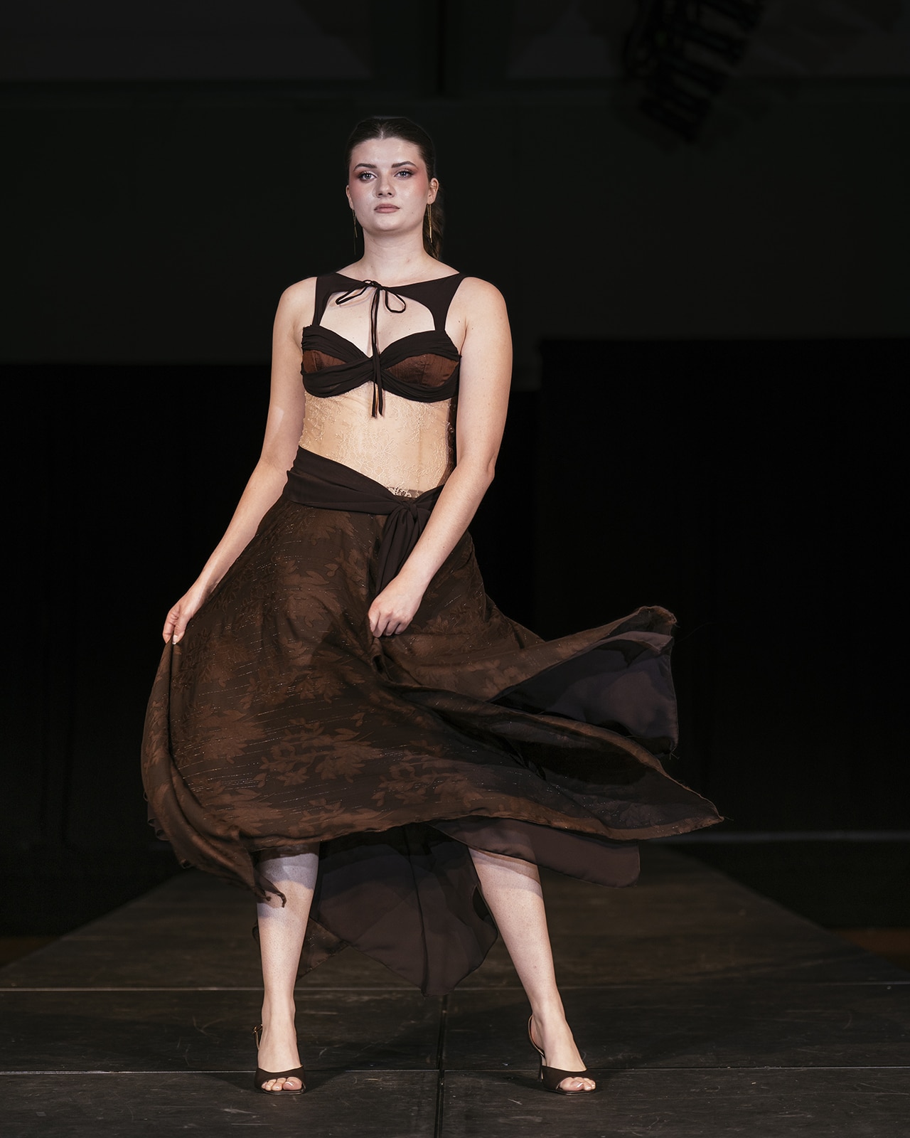 Model on the runway in a two piece brown outfit: skirt and top.