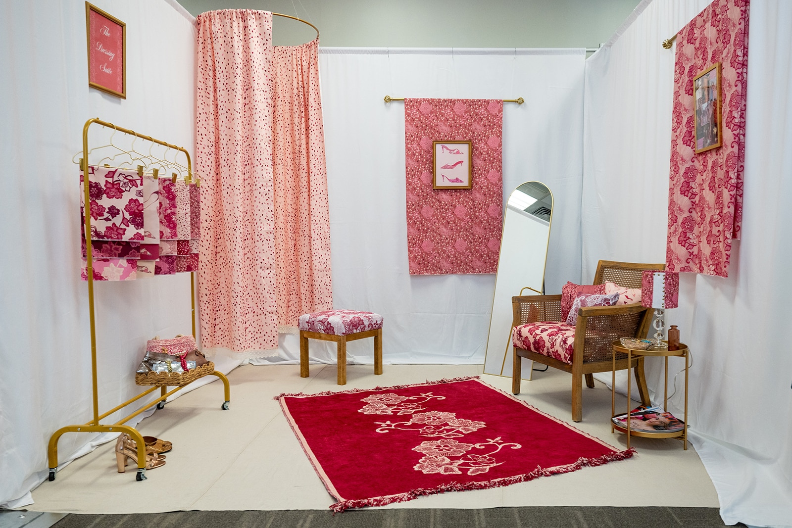 Photo of a room with a pink rug, pink chair, additional pink textiles hanging in the room.