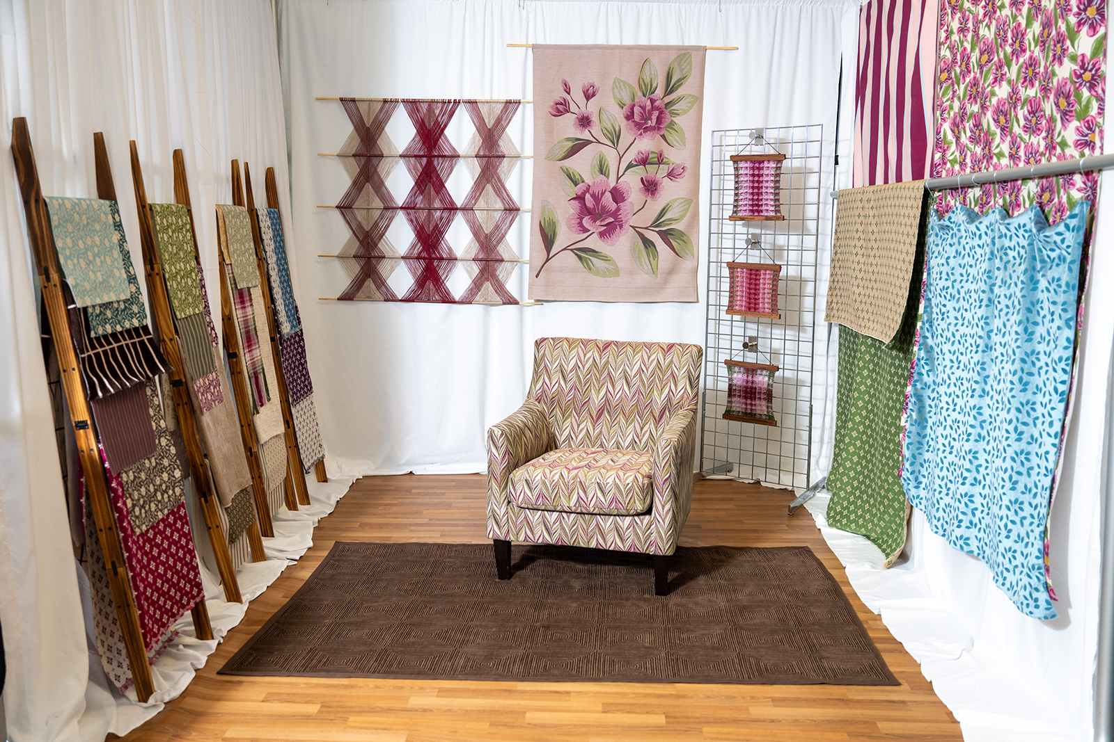 A photo with a room with one chair in it and other textiles hung on the other three walls.