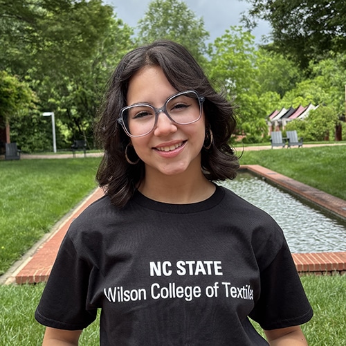 A person wearing a black t-shirt in front of a fountain.