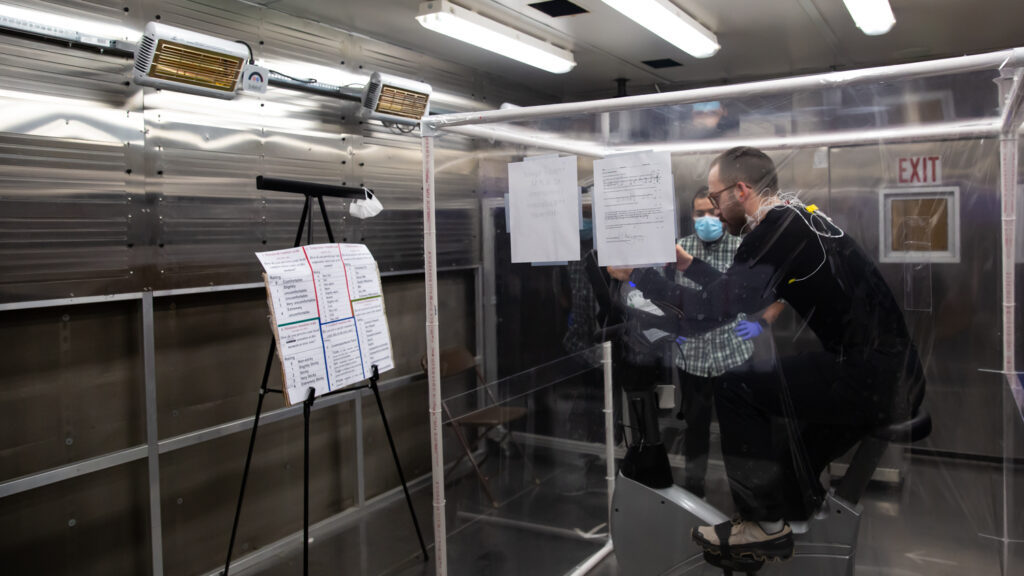 Doctoral student recording results from a human subject on a bike in a lab at the Textile Protection and Comfort Center in the Wilson College of Textiles.