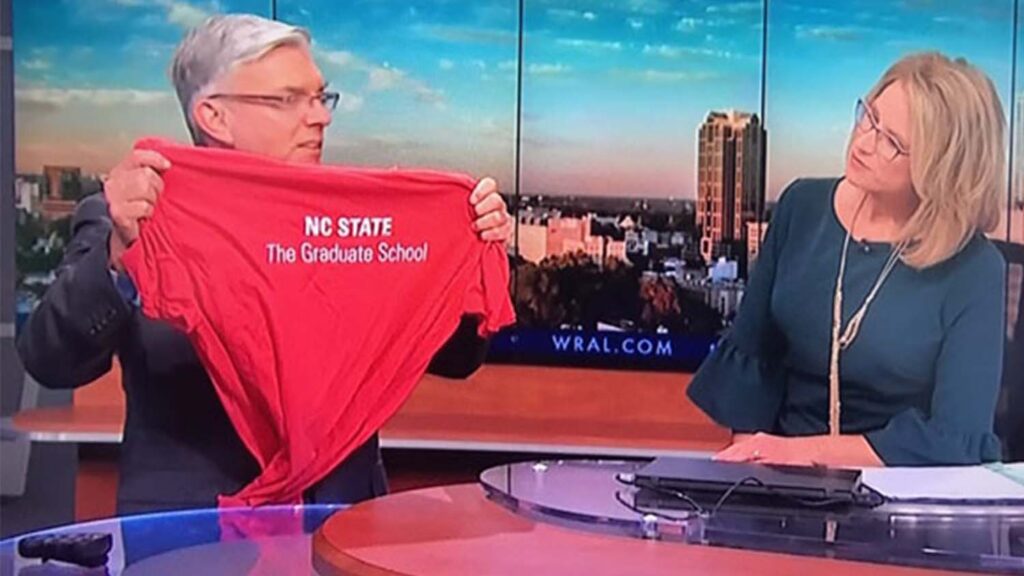 Greg Fishel, WRAL meteorologist and 3MT master of ceremonies, shows off his Graduate School t-shirt on the air