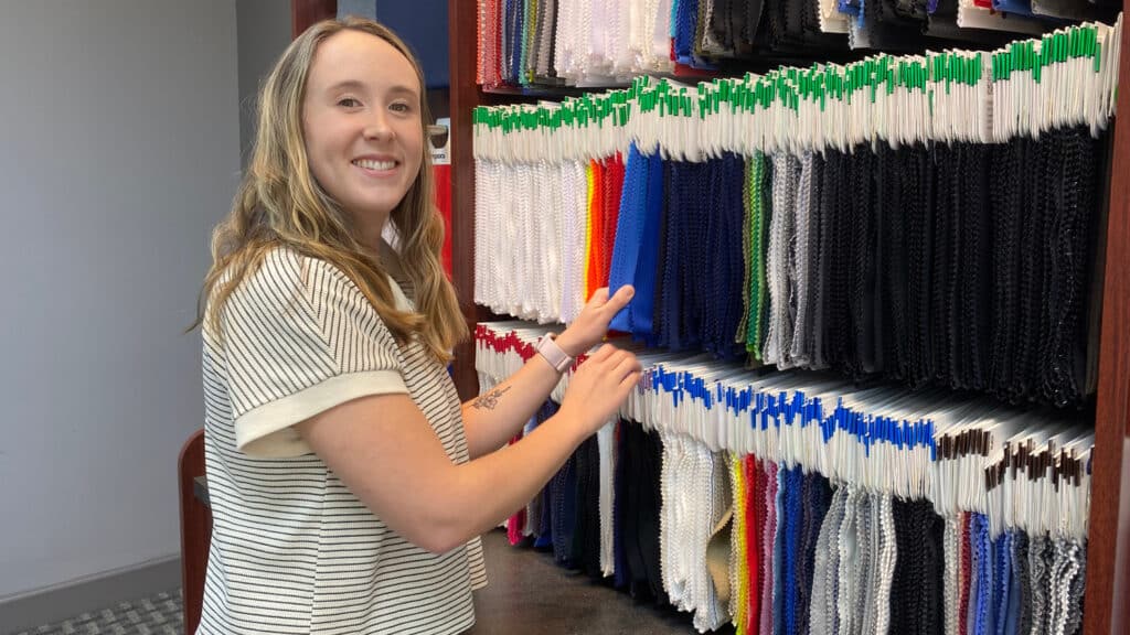 Hannah Orlowski standing in front of Contempora fabric swatches.