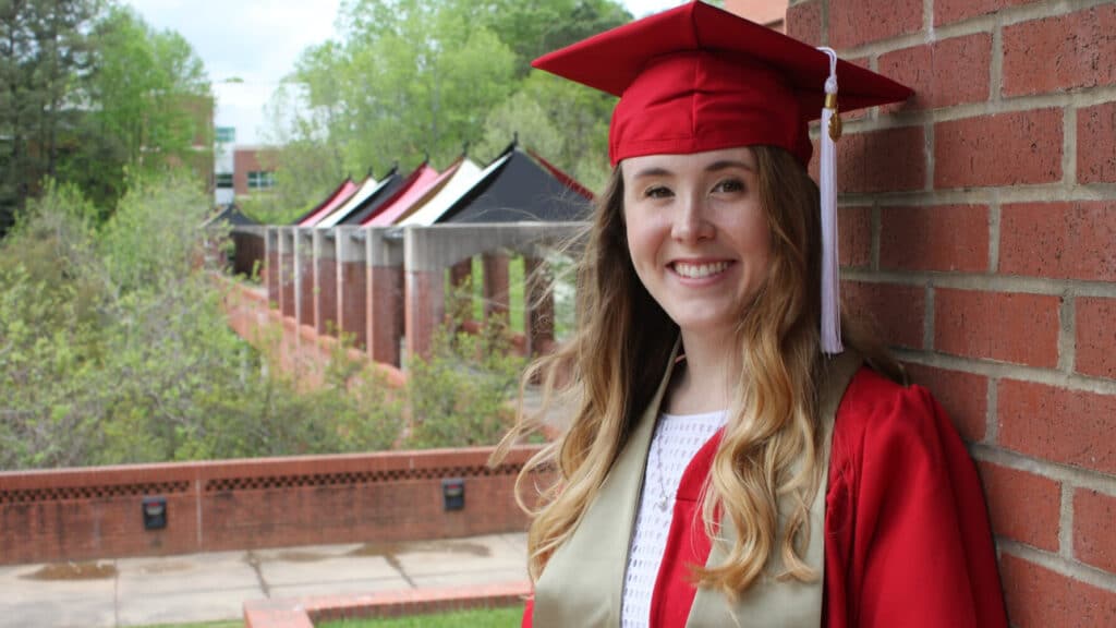 Hannah Orlowski wearing a graduation cap and gown at the Wilson College of Textiles.