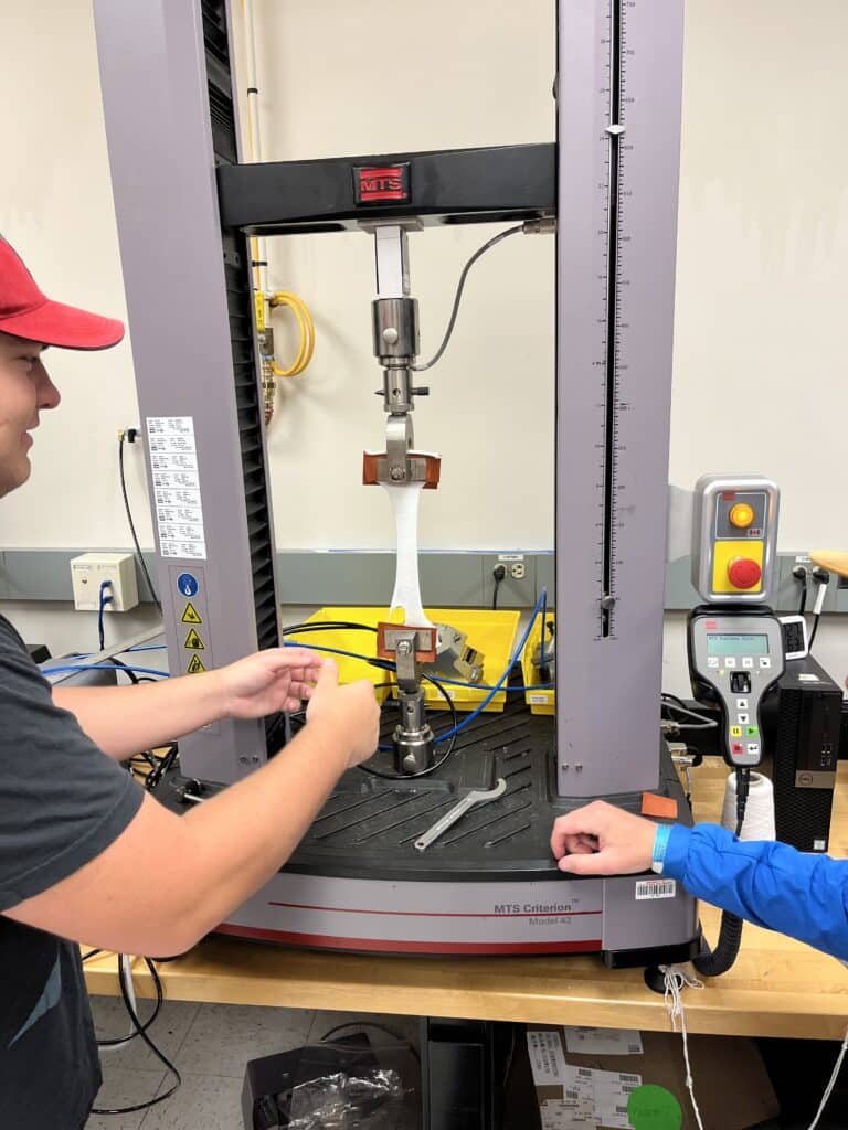 A team member conducts test using the MTS criterion machine that stretches material to test tensile properties.