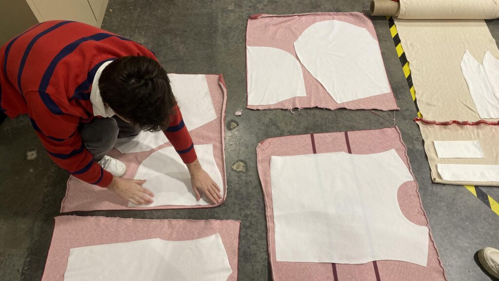 A team member lays flat patterns onto material to make a prototype. 