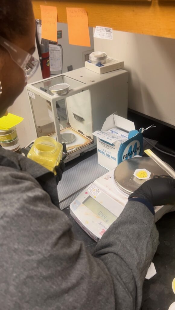 Team member weighs dye material in lab.