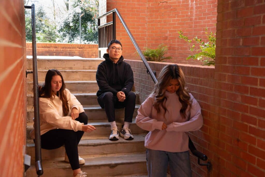 Team members pose on brick staircase modeling their hoodie prototypes. 