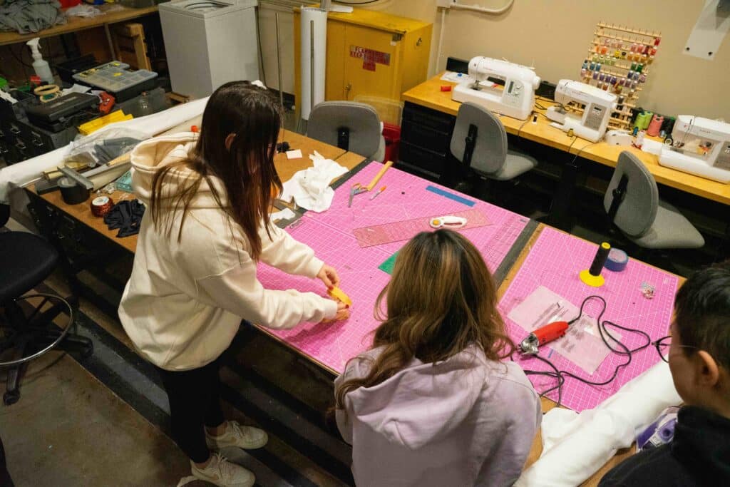 Team assembles prototype using sewing equipment in lab.