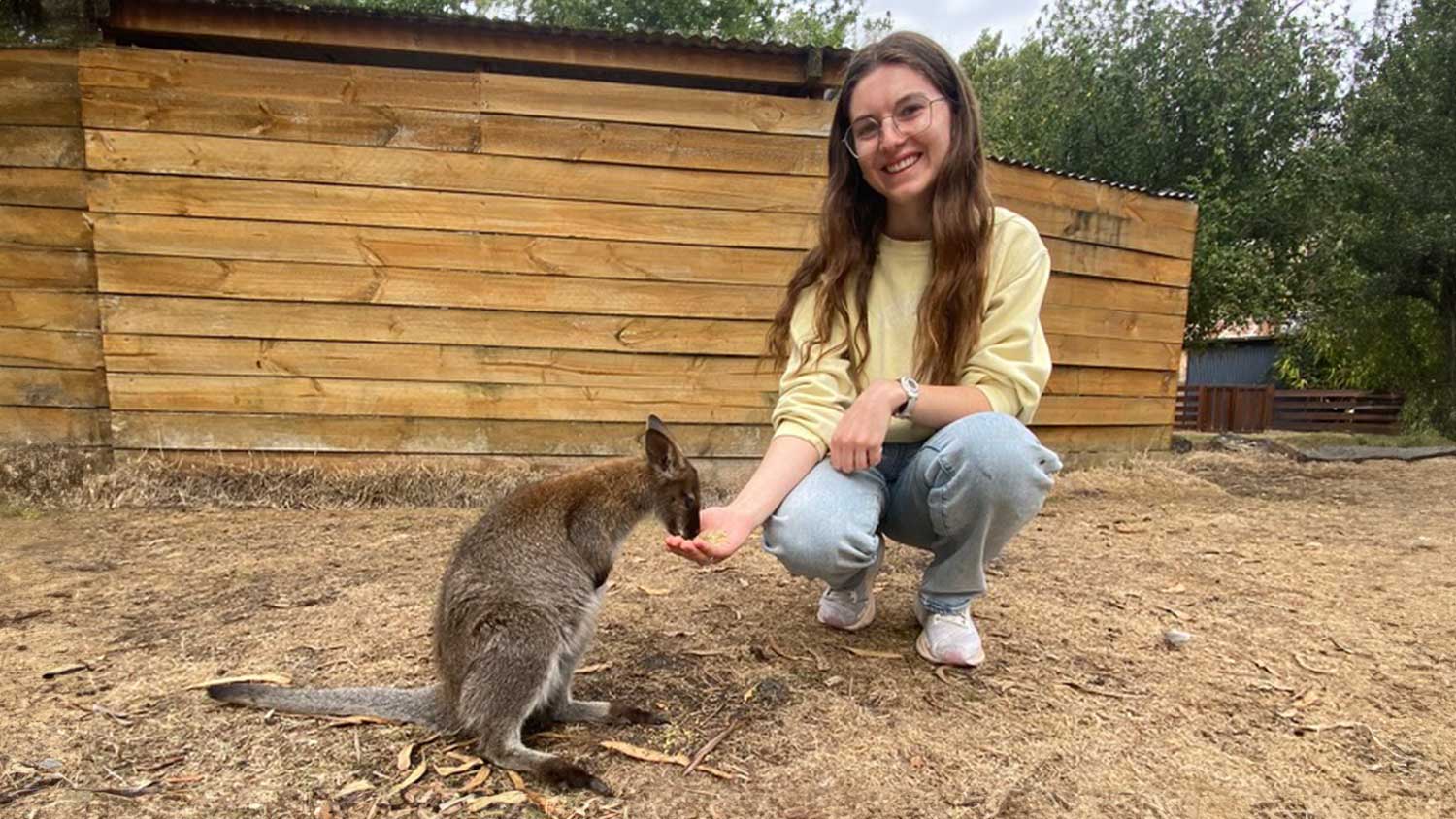 Student smiling while standing next to a kangaroo