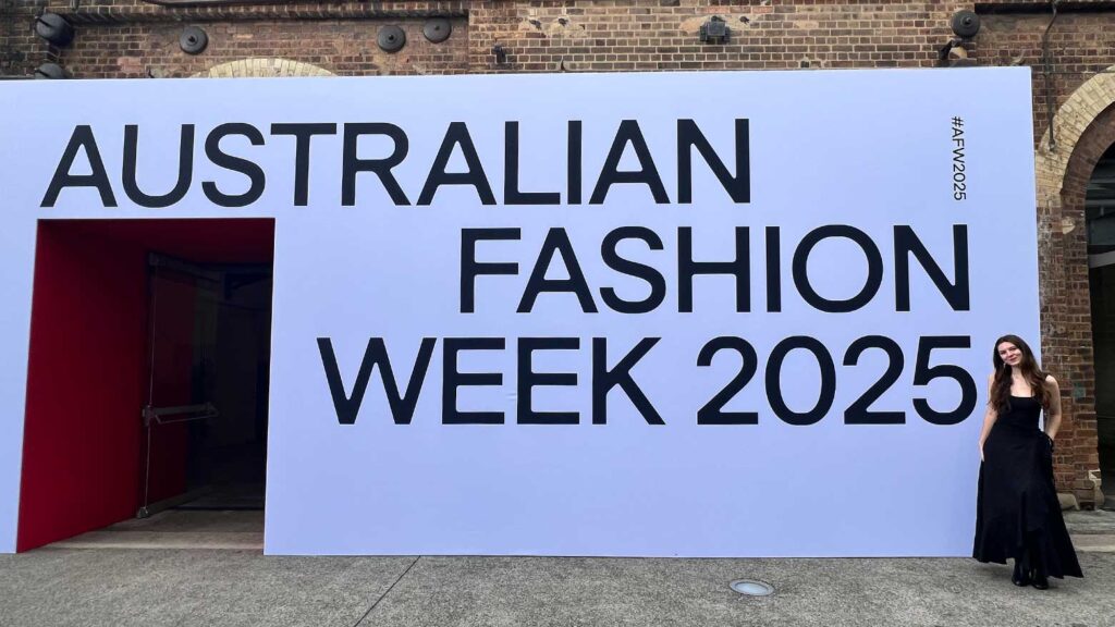 Kat Charrier standing next to a sign that says "Australian Fashion Week 2025."