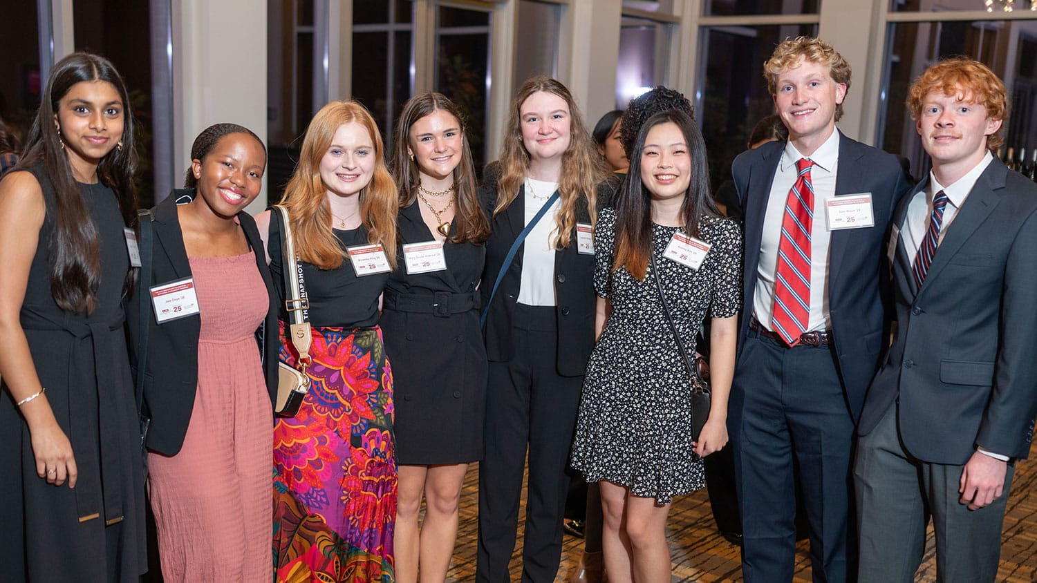 Eight students smiling while standing next to one another.