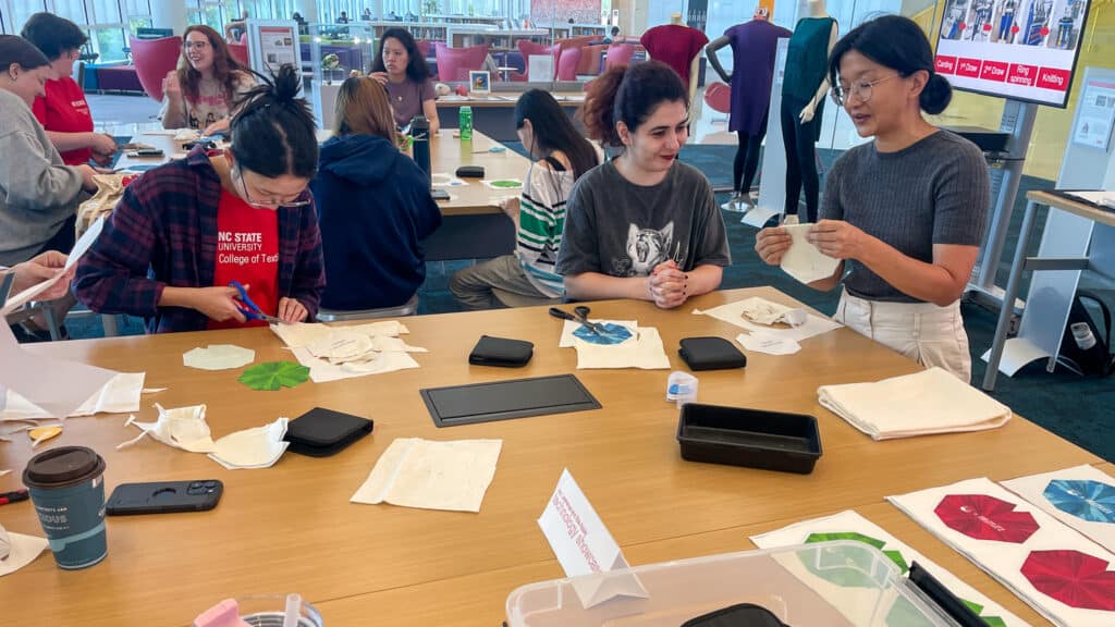 KC Soong shows a student the patterns for her DIY frog pincushion kit at the Hunt Library showcase.