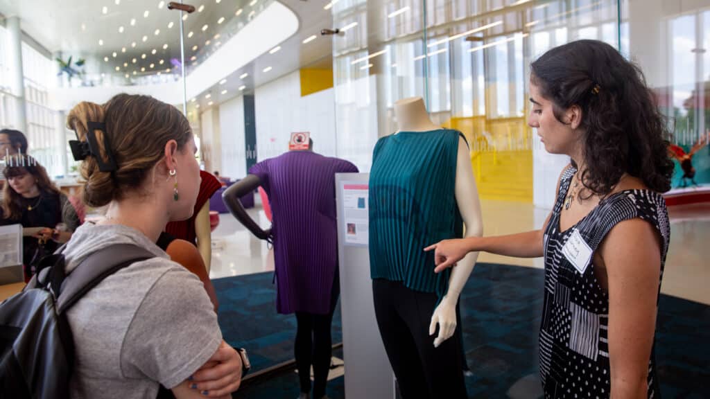 Olivia Jurney points out details on one of her Selene Tops to another student.