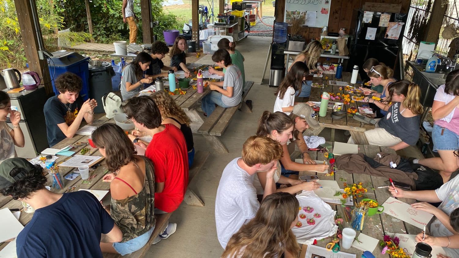 Students sit at picnic tables while participating in the Eco Design Outreach Club dye workshop.