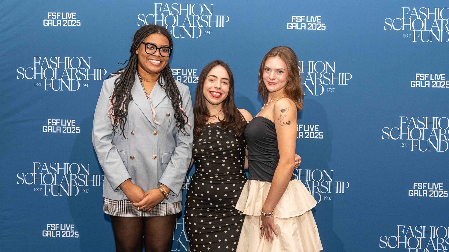 Rachel Kelly, Celia Fennell and Rosa Stancil pose and smile together in front of a blue step-and-repeat backdrop with "Fashion Scholarship Fund" and "FSF Live Gala 2025" printed on it.