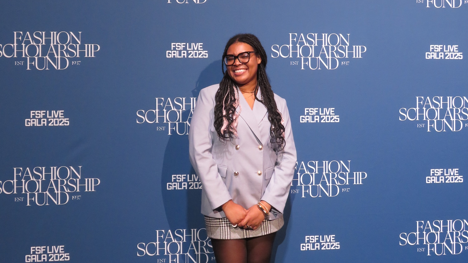 Celia Fennell poses and smiles in front of a blue step-and-repeat backdrop with "Fashion Scholarship Fund" and "FSF Live Gala 2025" printed on it.


