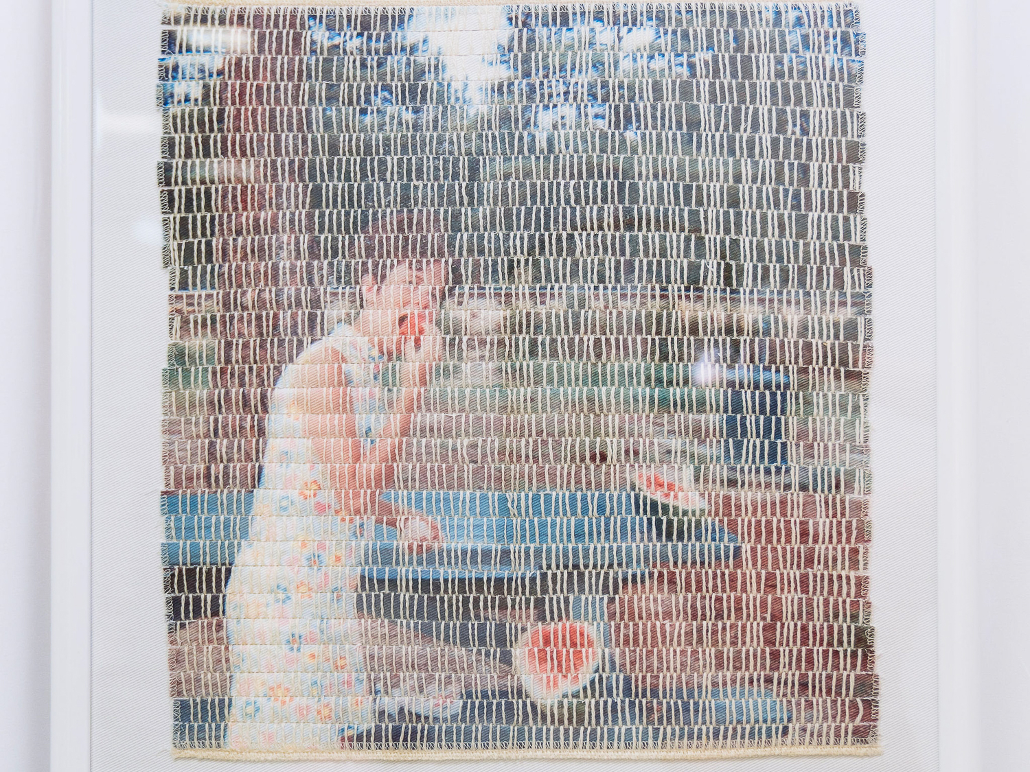 A woven work showing an image of a picnic scene featuring a woman in a floral, white dress eating a watermelon.