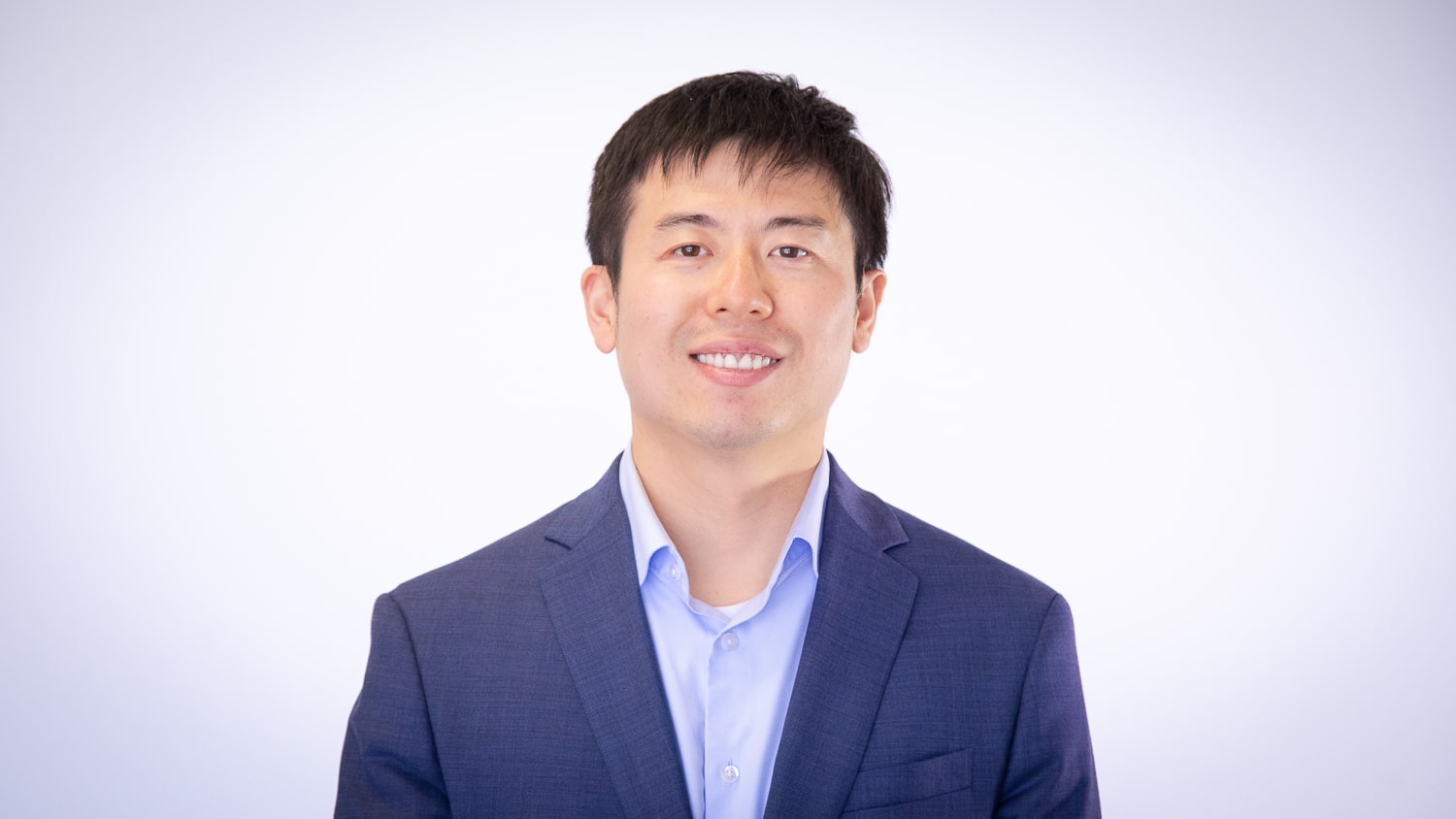 Yang Zhang stands in front of a white background.