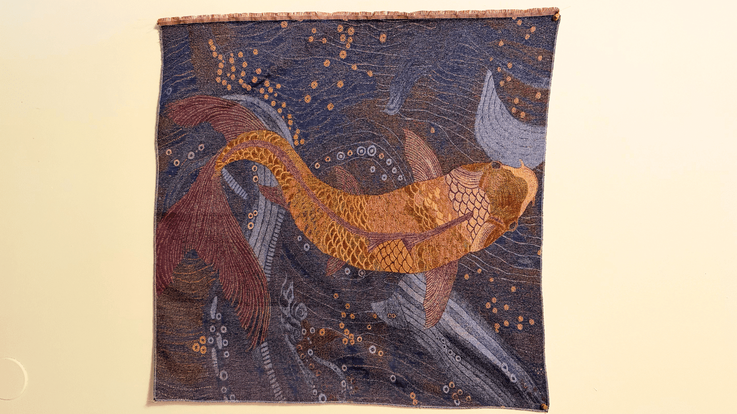 A woven tapestry of fish hangs on a wall
