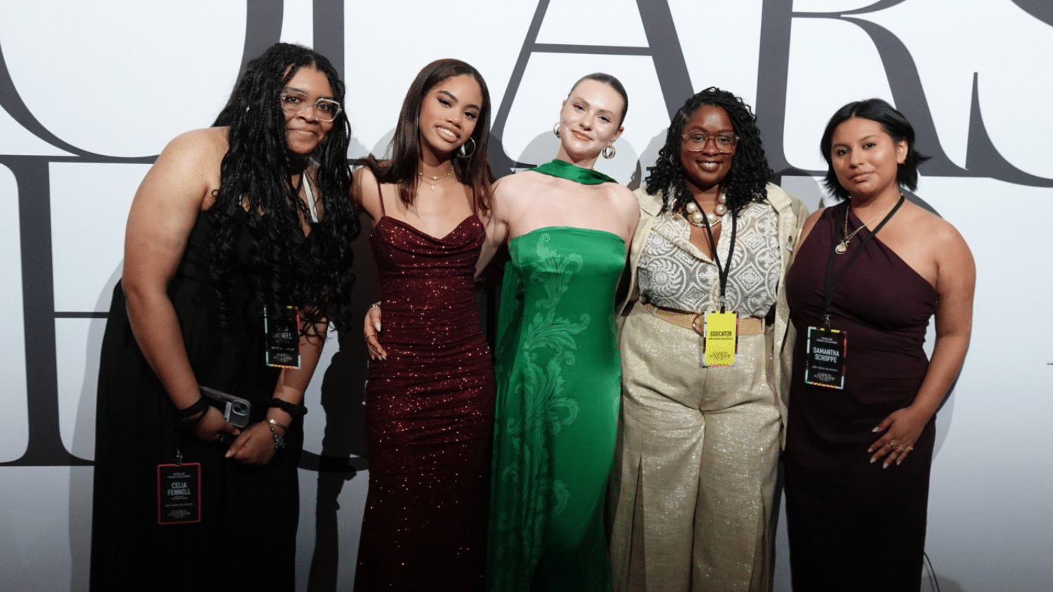 (From left to right) Celia Fennell, Kyla Perry, Jessica Singleton and Samantha Schoppe pose for a group photo in front of a white background with large black text.