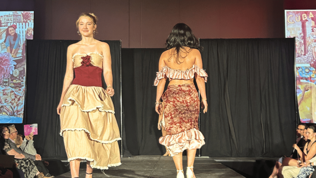 A two student pass each other while walking the runway of the African American Textile Society's Fashion Exposé.